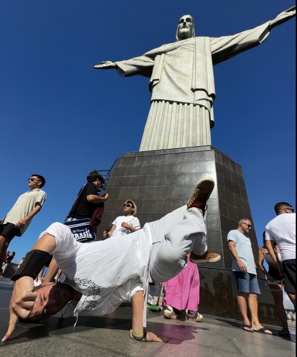 Breakdancer freezing on one hand at the base of Christ the Redeemer statue in Rio de Janeiro, Brazil